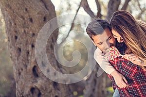 Portrait of smiling handsome man giving piggy back to his girlfriend in the nature