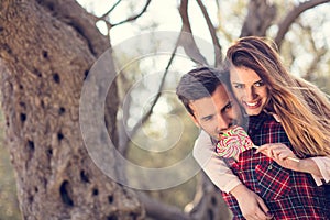 Portrait of smiling handsome man giving piggy back to his girlfriend in the nature