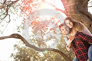 Portrait of smiling handsome man giving piggy back to his girlfriend in the nature