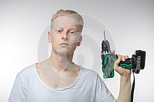 Portrait of a smiling handsome young man holding drill against white background