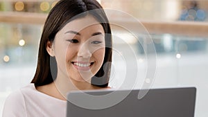 Portrait smiling happy asian female face looking at laptop satisfied girl woman freelancer boss worker manager typing