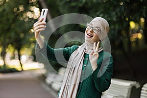 Portrait of smiling happy beautiful muslim woman relaxing using digital smartphone.