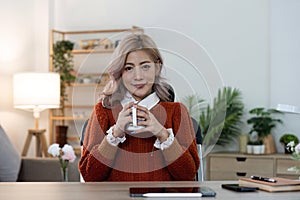 Portrait of smiling happy cheerful beautiful pretty asian woman relaxing drinking and looking at cup of hot coffee or