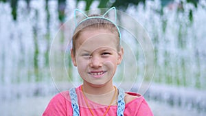 Portrait of a smiling, happy eight-year-old girl in a fun hoop with ears on her head, hair ornament. on the background