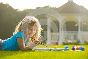 Portrait of smiling happy kid enjoying art and craft drawing in backyard or spring park. Children artist paints