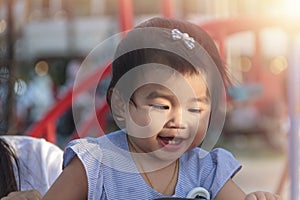 Portrait of smiling happy little girl enjoy with playground outdoor. Child playing on outdoor playground. Asian little girl play