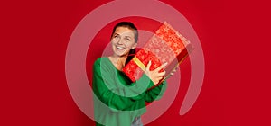 Portrait of smiling happy woman holding big present box isolated over red studio background. Cheerful