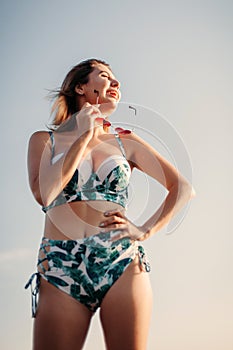 Portrait of a smiling happy young woman in bikini and sunglasses at sea in travel. concept of relaxation, recreation