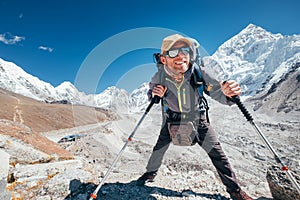 Portrait of smiling Hiker man with Nuptse 7861 m peak and Gorak shep settlement background with trekking poles, UV protecting