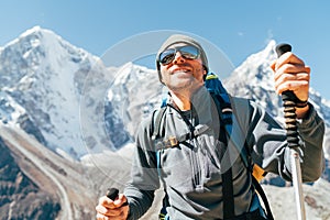 Portrait of smiling Hiker man on Taboche 6495m and Cholatse 6440m peaks background with trekking poles, UV protecting sunglasses.