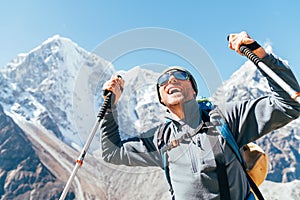 Portrait of smiling Hiker man on Taboche 6495m and Cholatse 6440m peaks background with trekking poles, UV protecting sunglasses.