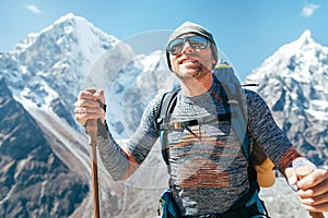 Portrait of smiling Hiker man on Taboche 6495m and Cholatse 6440m peaks background with trekking poles, UV protecting sunglasses.