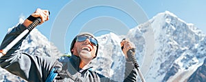 Portrait of smiling Hiker man on Taboche 6495m and Cholatse 6440m peaks background with trekking poles, UV protecting sunglasses.