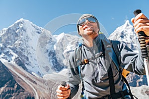 Portrait of smiling Hiker man on Taboche 6495m and Cholatse 6440m peaks background with trekking poles, UV protecting sunglasses.