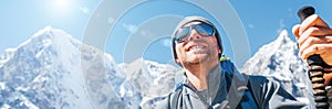 Portrait of smiling Hiker man on Taboche 6495m and Cholatse 6440m peaks background with trekking poles, UV protecting sunglasses.