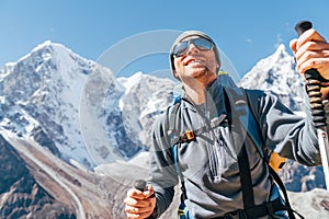 Portrait of smiling Hiker man on Taboche 6495m and Cholatse 6440m peaks background with trekking poles, UV protecting sunglasses. photo