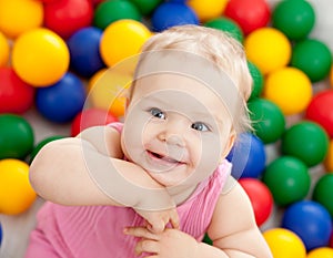 Portrait of a smiling infant among colorful balls