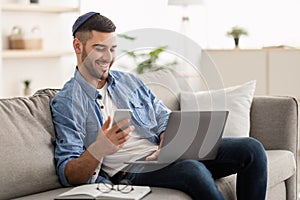 Happy jewish man using mobile phone and laptop