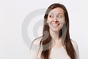 Portrait of smiling joyful pretty young woman in light clothes standing and looking aside isolated on white wall