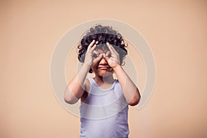 A portrait of smiling kid boy showing binocular gesture. Children and emotions concept