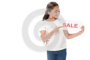 portrait of smiling kid pointing at sale banner in hand