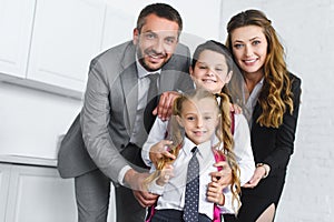 portrait of smiling kids in school uniform with backpacks and parents in suits