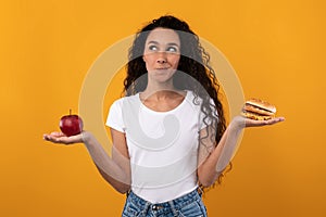Portrait of Smiling Latin Lady Holding Apple And Burger