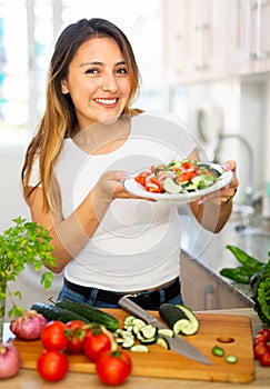 Portrait of smiling latino woman serving fresh healthy salad