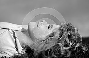 Portrait of a smiling little boy lying on green grass. Happy children relax on green grass in spring park. Healthy