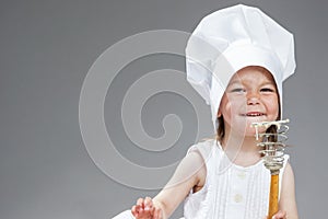 Portrait of Smiling Little Caucasian Girl in Cook Uniform Posing with Whisk