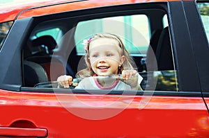 Portrait smiling little child sitting in red car