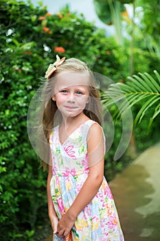 Portrait of a smiling little girl. Girl on the background of greenery in the tropics