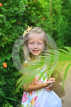 Portrait of a smiling little girl. Girl on the background of greenery in the tropics