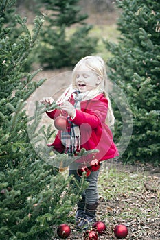 Portrait of smiling little girl hanging baubles on trees