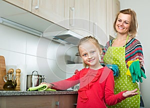 Little girl and mom tidy up at kitchen photo