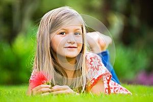 Portrait of a smiling little girl lying on green grass