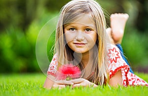 Portrait of a smiling little girl lying on green grass