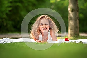 Portrait of a smiling little girl lying on green grass