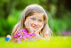 Portrait of a smiling little girl lying on green grass