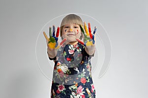 Portrait of a smiling little girl with painted hands and cheeks on an isolated white background