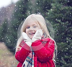 Portrait of smiling little girl standing in snowfall