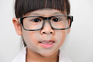 Portrait of a smiling little girl wearing glasses in a doctor or science costume on a white background. Little scientist