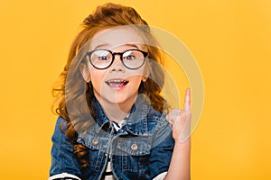 portrait of smiling little kid in eyeglasses pointing up