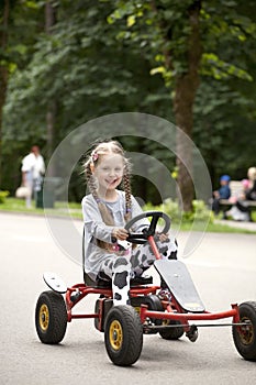 Portrait of a smiling littlel girl driving the car in amusement