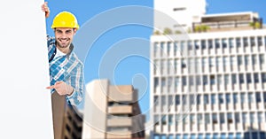 Portrait of smiling male architect pointing at blank billboard against buildings