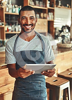 Portrait of smiling male cafe owner holding digital tablet