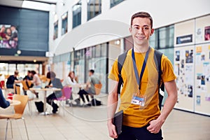 Portrait Of Smiling Male College Student In Busy Communal Campus Building