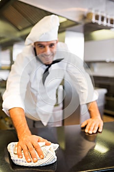 Portrait of a smiling male cook wiping kitchen counter