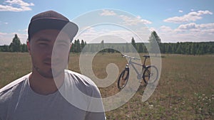 Portrait of Smiling Male Cyclist Showing Thumbs Up Gesture. Behind Him is a Bicycle. Cycling is Cool. Free Traveler