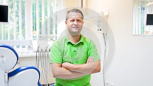 Portrait of smiling male dentist sitting in his dental clinic